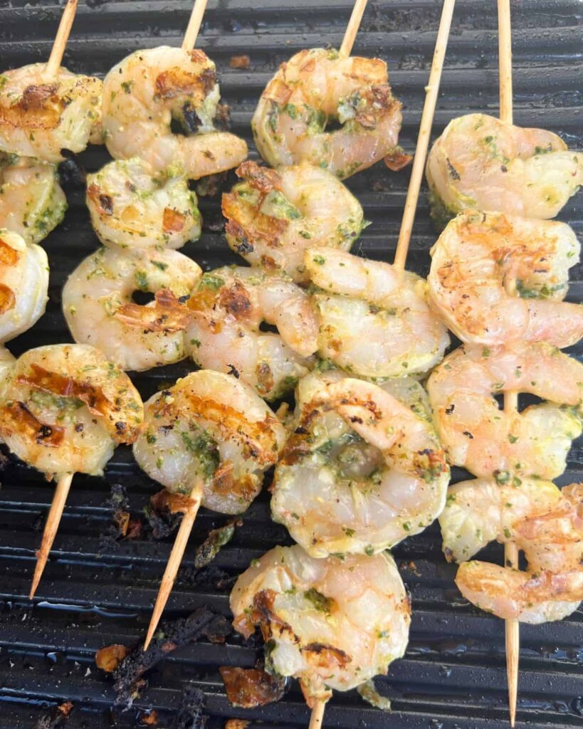 Pesto Shrimp Kabobs cooking on an outdoor griddle. 