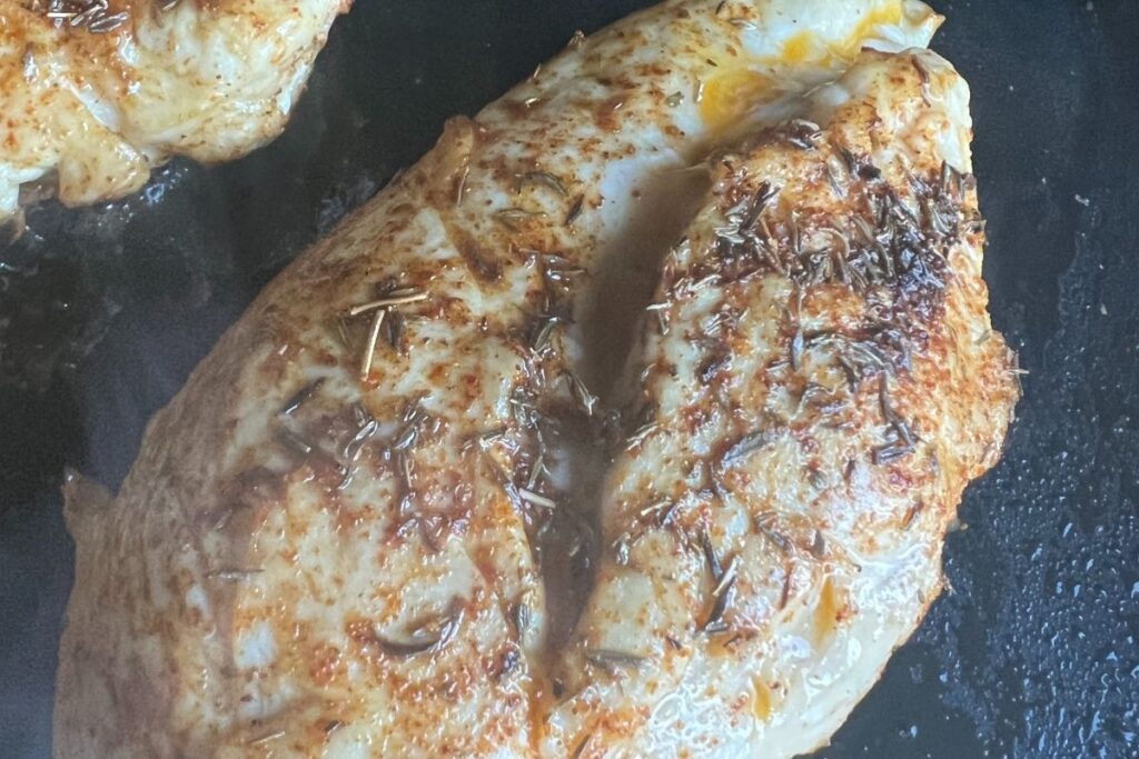 Fully cooked seasoned chicken breasts on a Blackstone griddle. 