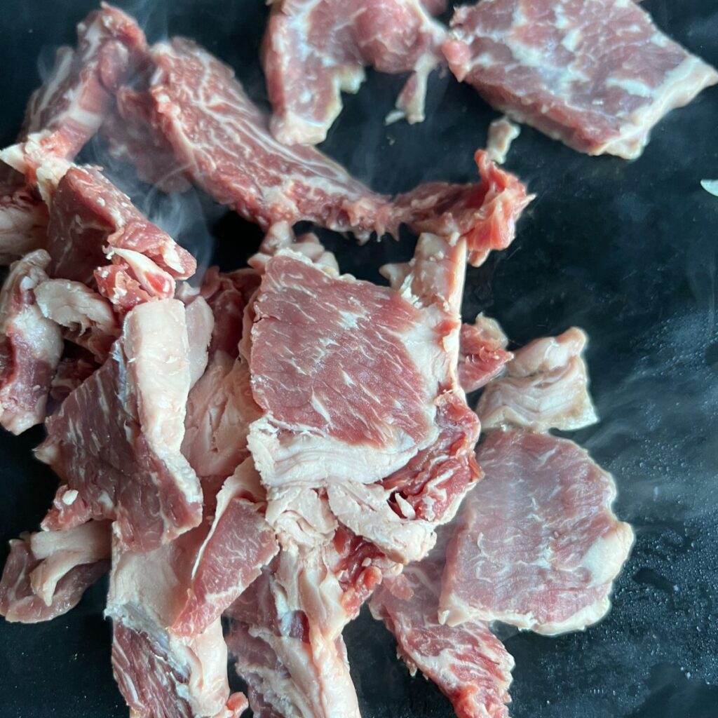 Sliced steak cooking on a Blackstone. 