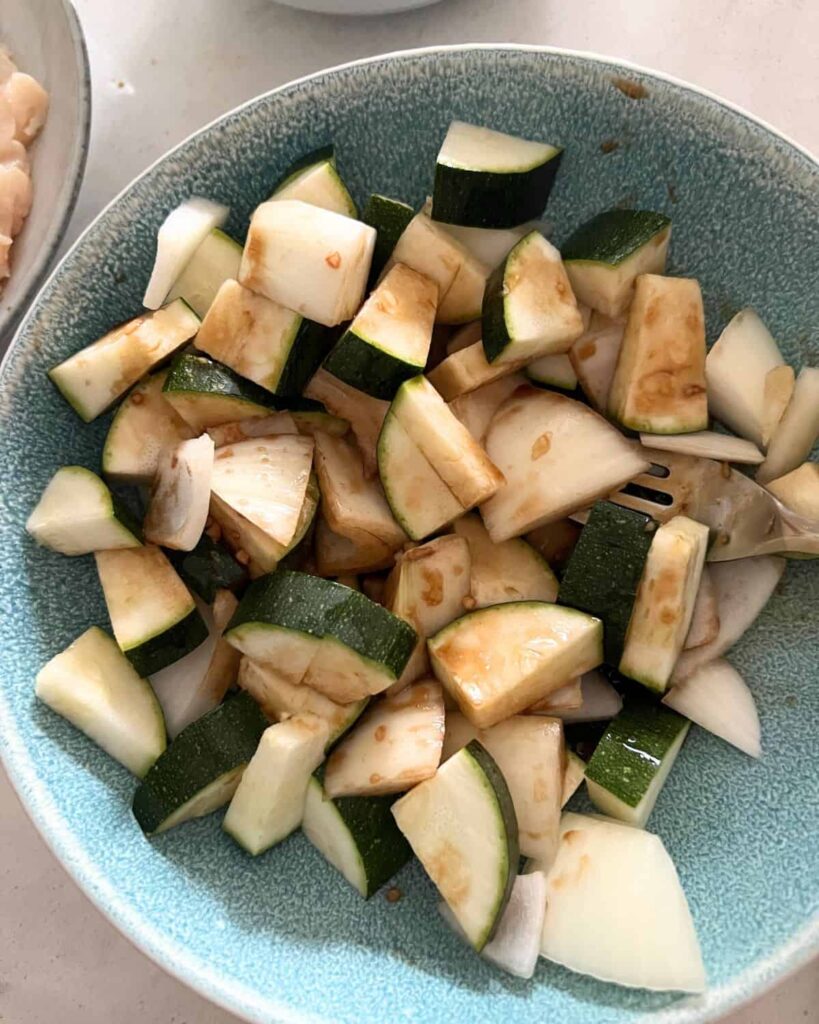 Onions in chopped zucchini mixed together in a bowl. 