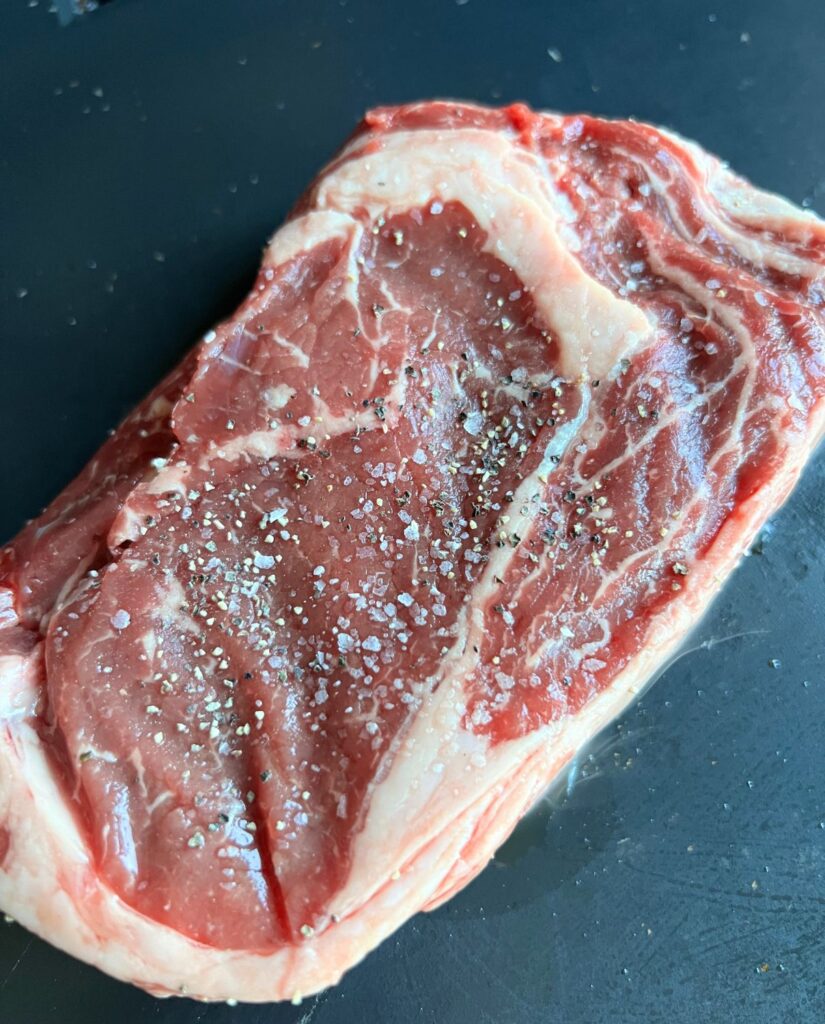 Raw seasoned steak with salt and pepper. 
