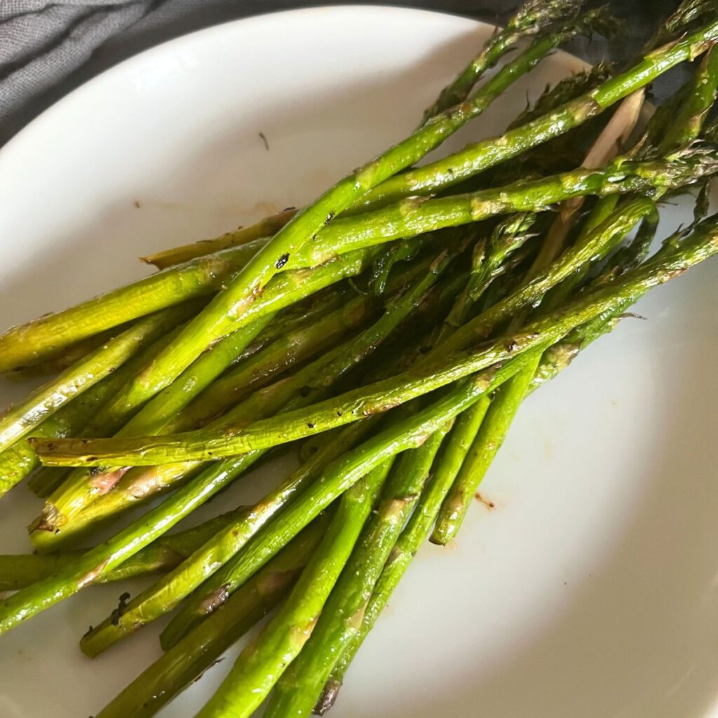 Seasoned cooked asparagus on griddle. 
