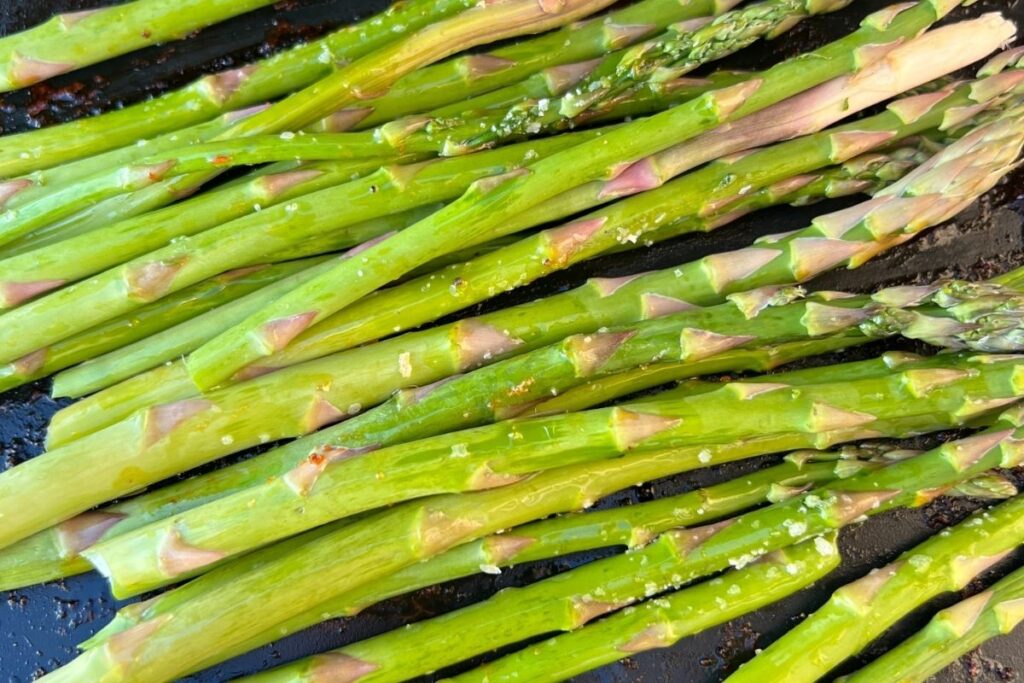 Seasoned asparagus cooing on griddle. 